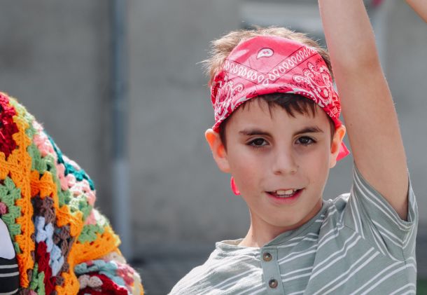 Child with disabilities wearing a bandana and raising his hand at the Mission to Ukraine Summer camp.