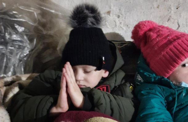 Ukrainian child praying in a bomb shelter during the war.