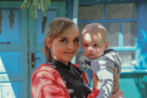 Vera and her baby in front of their house in Ukraine during the war after being helped with Mission to Ukraine.